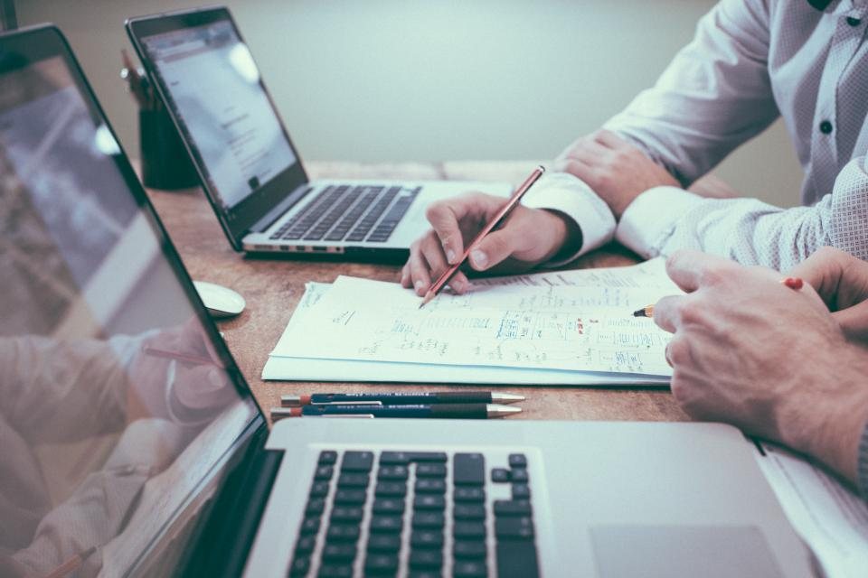 Documents, notes et ordinateurs sur une table de travail.